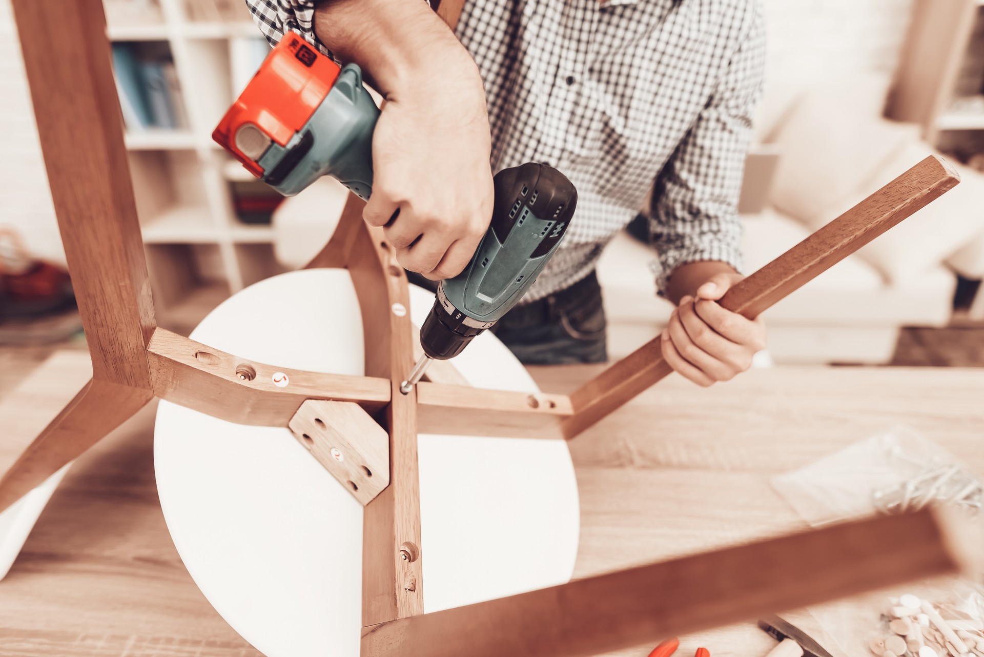 Furniture Assembler with Drill in Hands Repairs Chair.